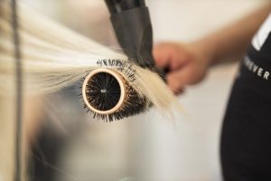 Kapper demonstreert persoonlijke verzorging met schone kleding en verzorgd uiterlijk in professionele omgeving